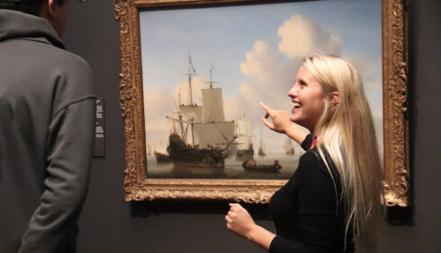 Woman pointing at a painting. A man looking at art.
