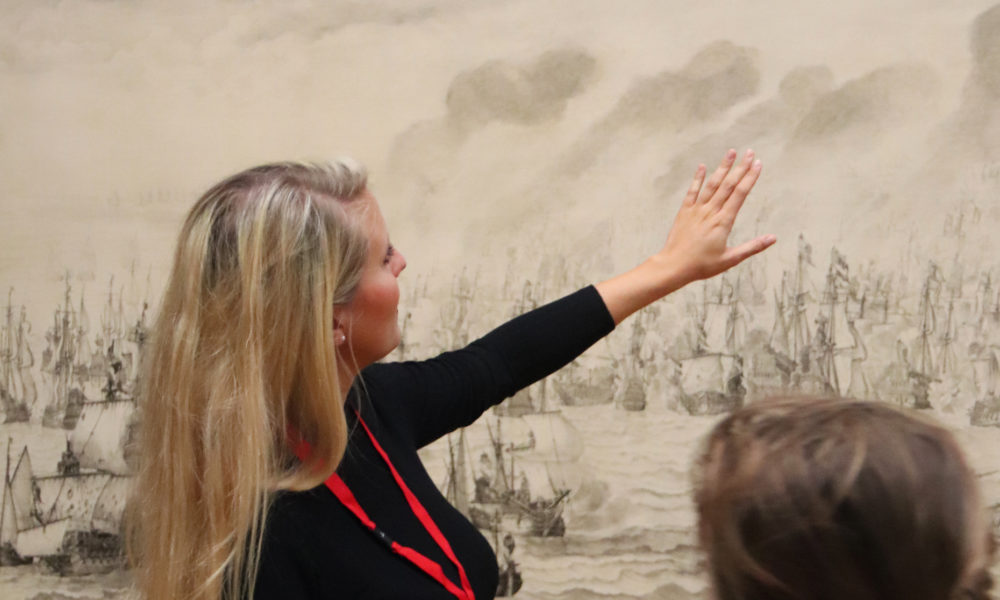 Tour guide explaining a historical painting to a tourist. Amsterdam city trip.