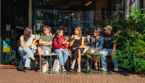 Group of friends chatting outside a cafe. Young people enjoying a sunny day in Amsterdam.