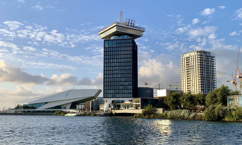 Modern buildings in Amsterdam by the water. The cityscape features sleek architecture.