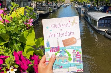 Glücksortebuch Amsterdam vor einer blumigen Gracht