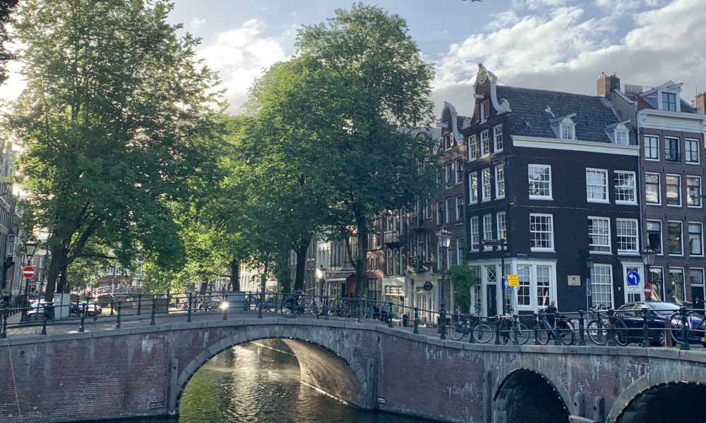 A scenic bridge over a canal in Amsterdam. The bridge has multiple arches.