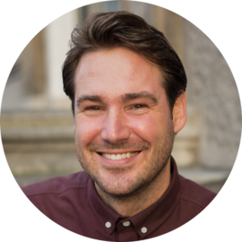 A smiling man with short brown hair wearing a maroon shirt. He appears friendly and approachable.