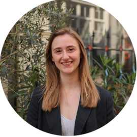 Portrait of a young woman smiling outdoors. Amsterdam city guide.