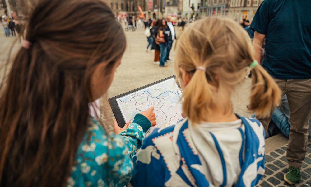 Two children looking at a digital map. They are planning their trip to Amsterdam.