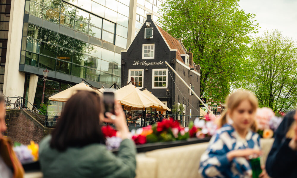 People on a city trip in Amsterdam. A traditional Dutch house in the background.