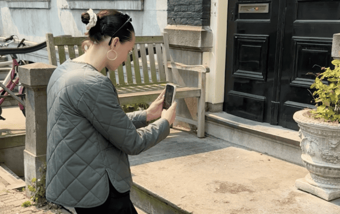 A woman taking a photo of a house in Amsterdam
