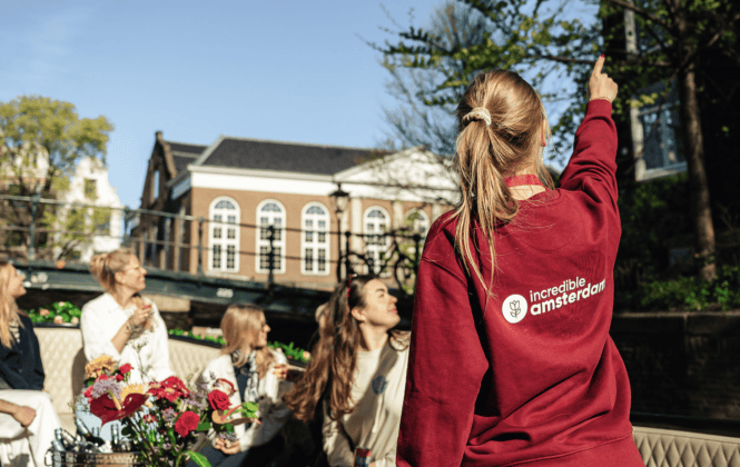 A guide pointing at a landmark in Amsterdam. A group of tourists on a guided tour in Amsterdam.